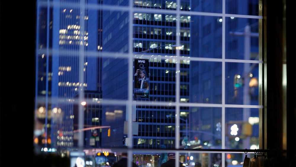 Nighttime view through window of glowing city skyscrapers and street traffic in Randolph's Bar & Lounge at Warwick New York