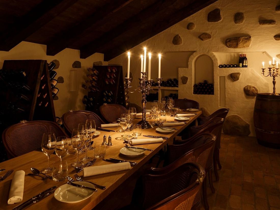 Candlelit dining table in a cozy wine cellar at Kokkedal Slot Copenhagen by Warwick in Hørsholm.