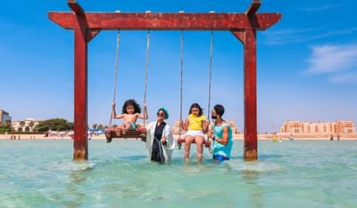 A family in the swings at the beach near Bay La Sun Hotel & Marina