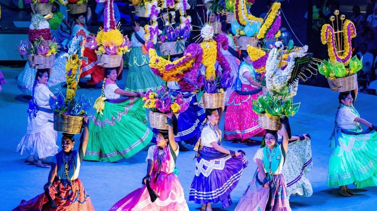 Traditional dancers in colorful skirts at a festival near Camino Real Pedregal Mexico, carrying floral baskets