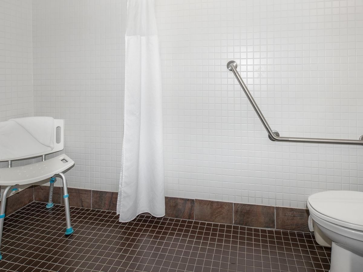 Accessible bathroom with shower chair and grab bar.