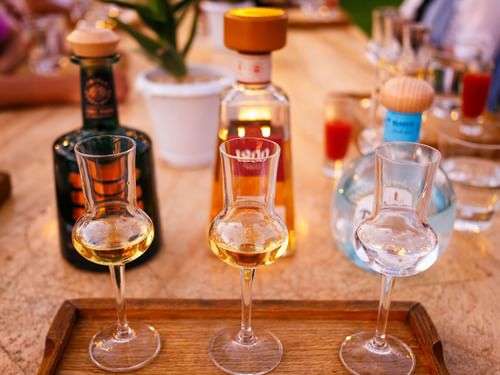 Flight of three tequila tasters, one clear and two amber, on a wooden tray in Bar La Suerte at Hacienda del Mar Los Cabos