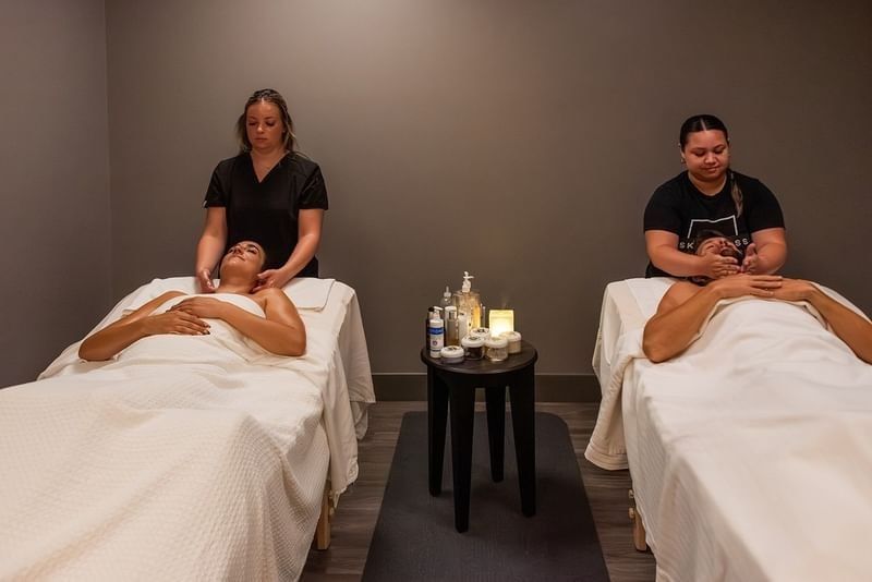 Two people receiving professional facial and neck massages in a tranquil spa room at Shangri-La Resort and Golf Club