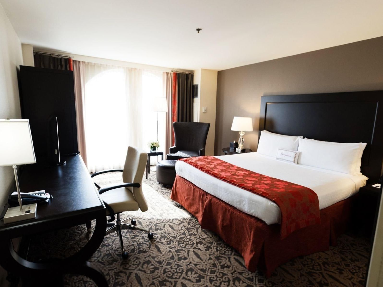 king bed in hotel room with desk and window
