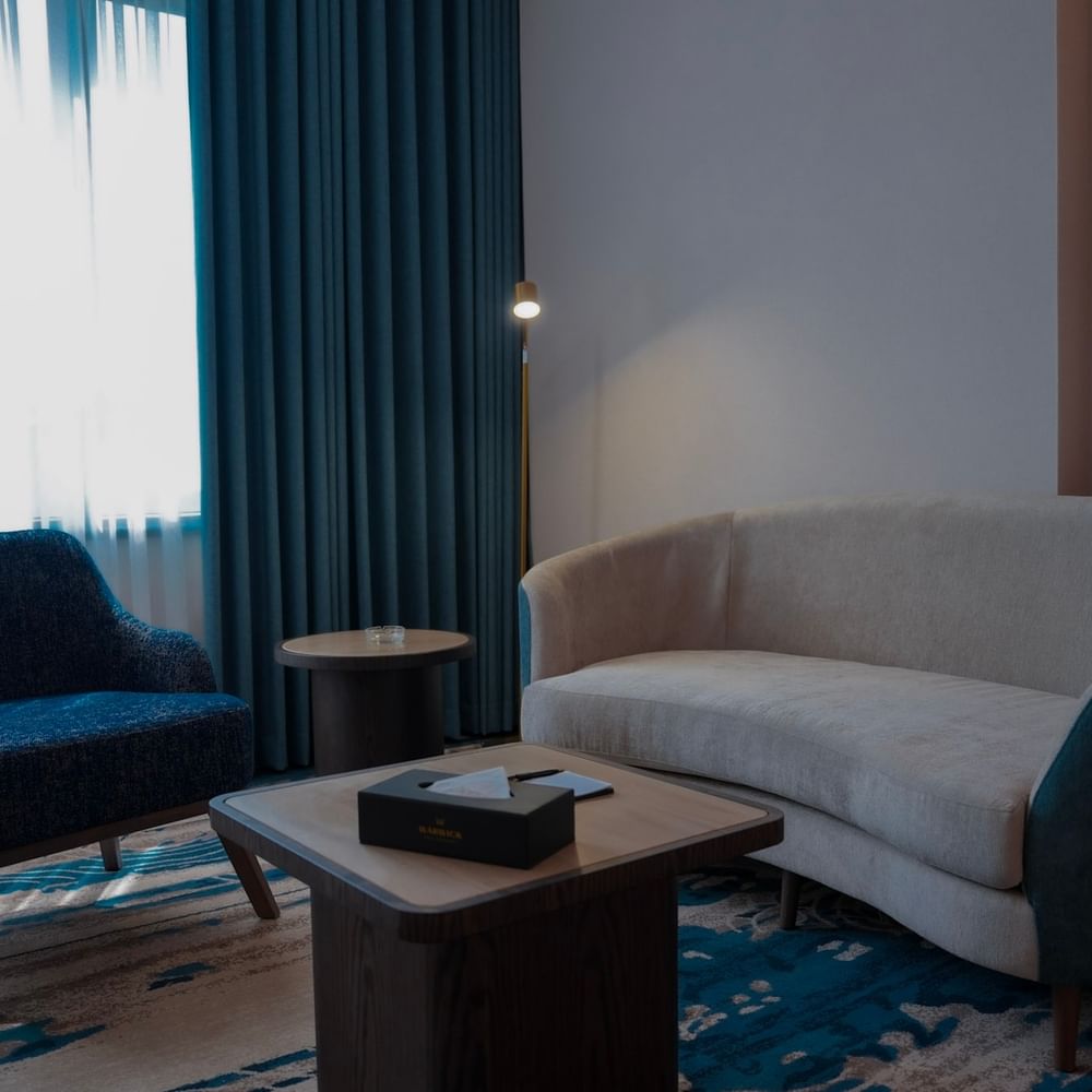 Living area with blue chairs and couch in Premium Club Room at Warwick Hotel & Spa - Jeddah.