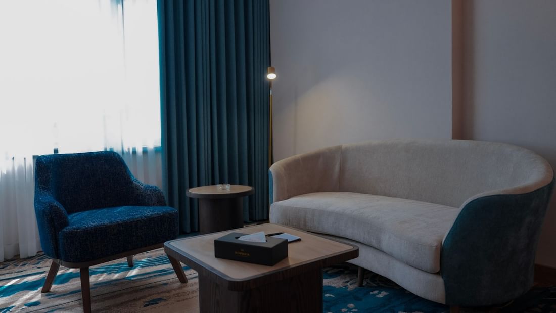 Living area with blue chairs and couch in Premium Club Room at Warwick Hotel & Spa - Jeddah.