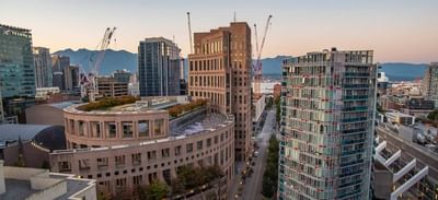 Aerial view of the Vancouver Public Library near Rosedale on Robson Suite Hotel, with mountains in the background