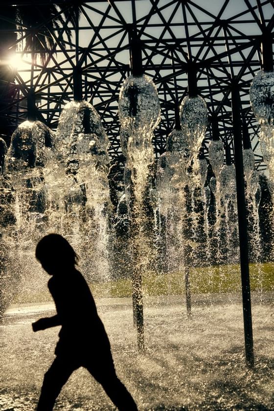 A kid playing at Treasury Gardens fountain near The Kinson