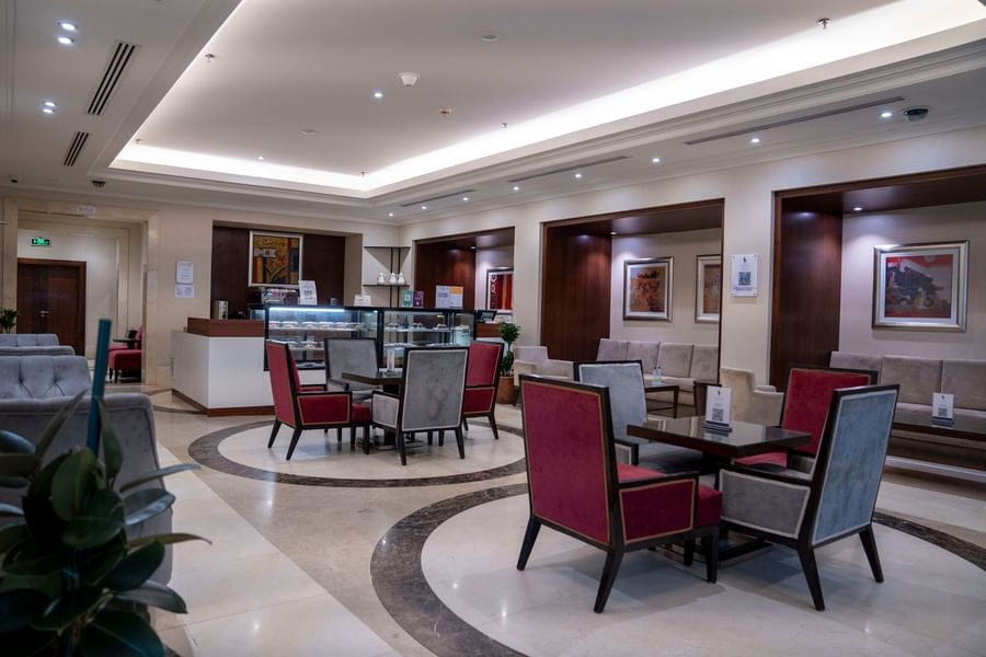 Lobby cafe area features stylish red and grey armchairs and circular floor tiling at Saja by Warwick Makkah