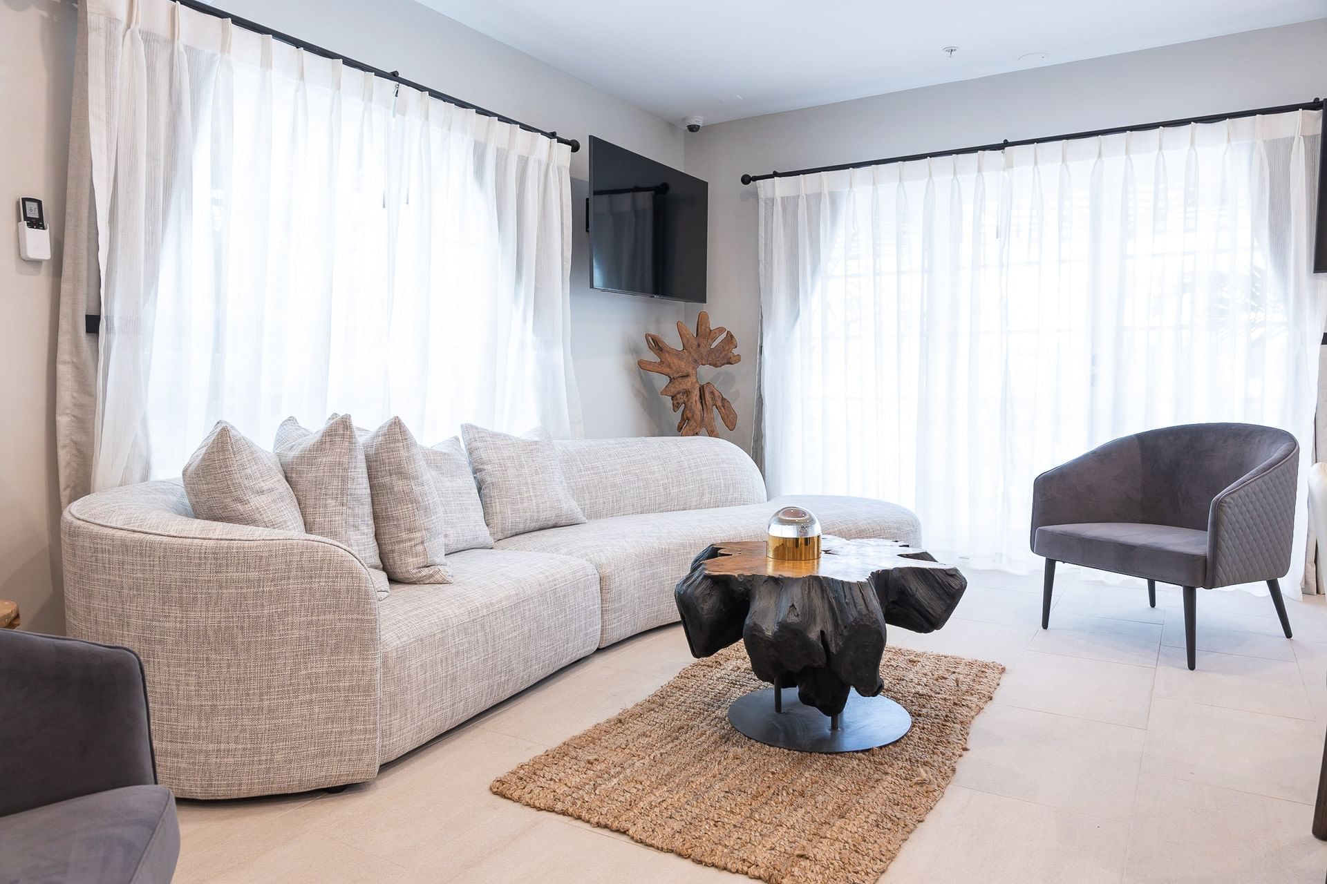A modern living room with a curved sofa, armchair, and unique coffee table.