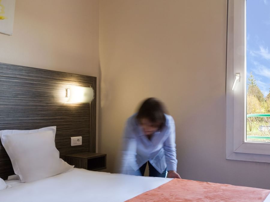 A Woman preparing a Standard Double bed at Hotel L'Acropole