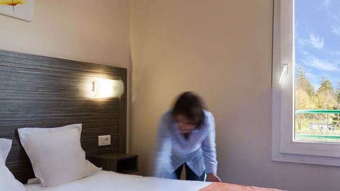 A Woman preparing a Standard Double bed at Hotel L'Acropole