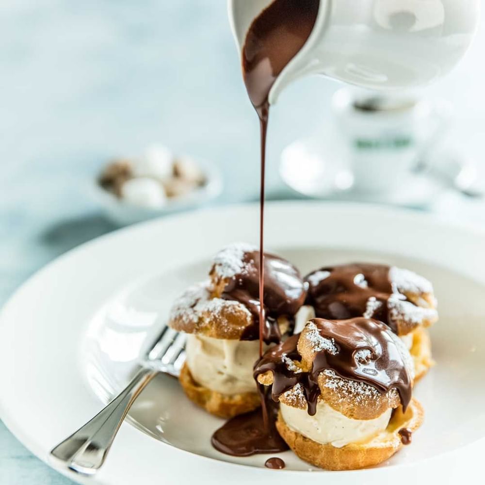 Close-up of chocolate sauce poured over profiteroles on a plate in Bistro Guillaume at Crown hotels Perth