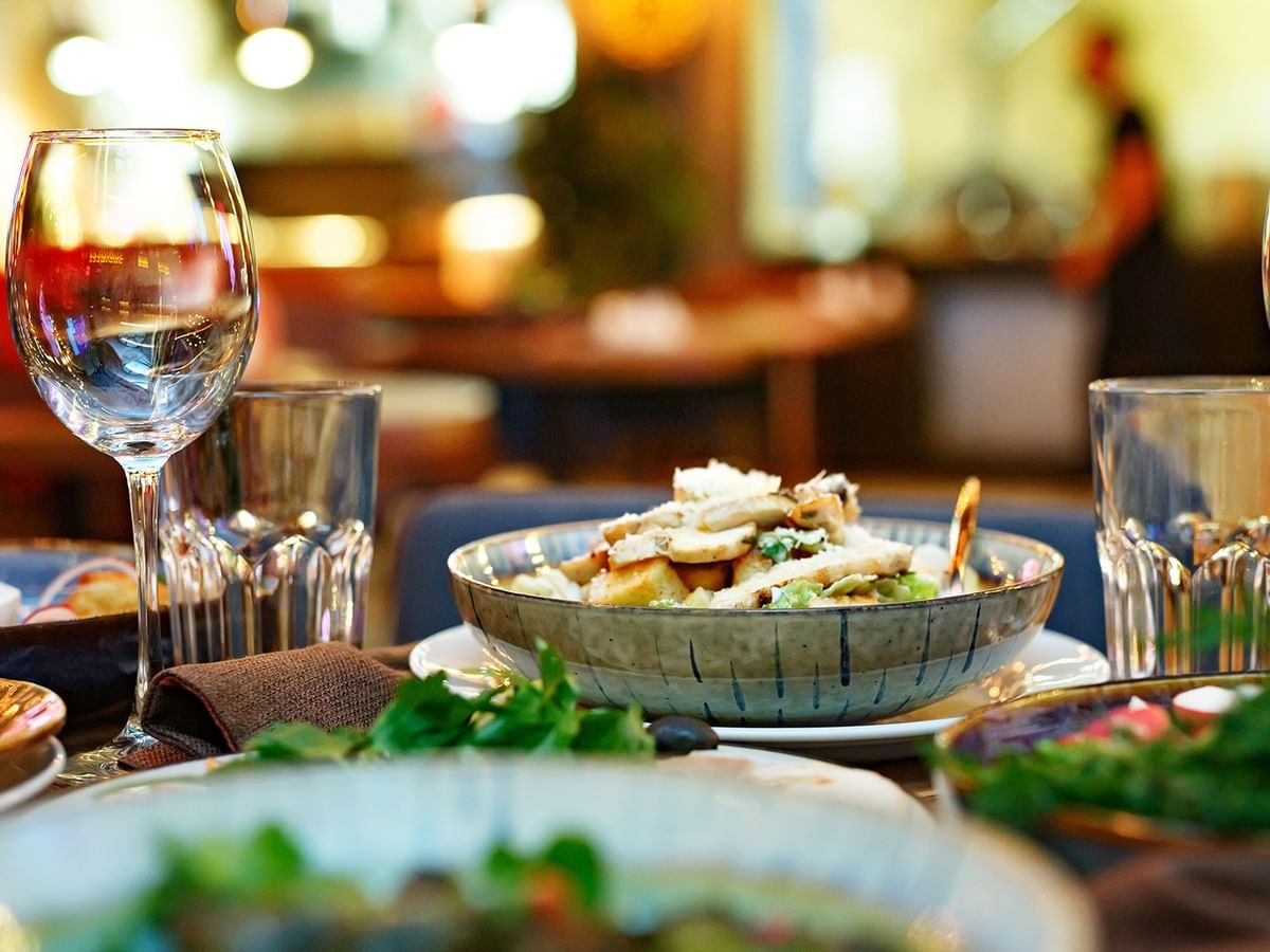 Elegant table setting with wine glasses and plated dishes at ATLAS steak + fish in Coast Langley City Hotel & Convention Centre