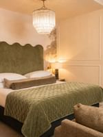 Studio Apartment with olive green upholstered headboard, crystal chandelier, and white wardrobes at The Capital Hotel.