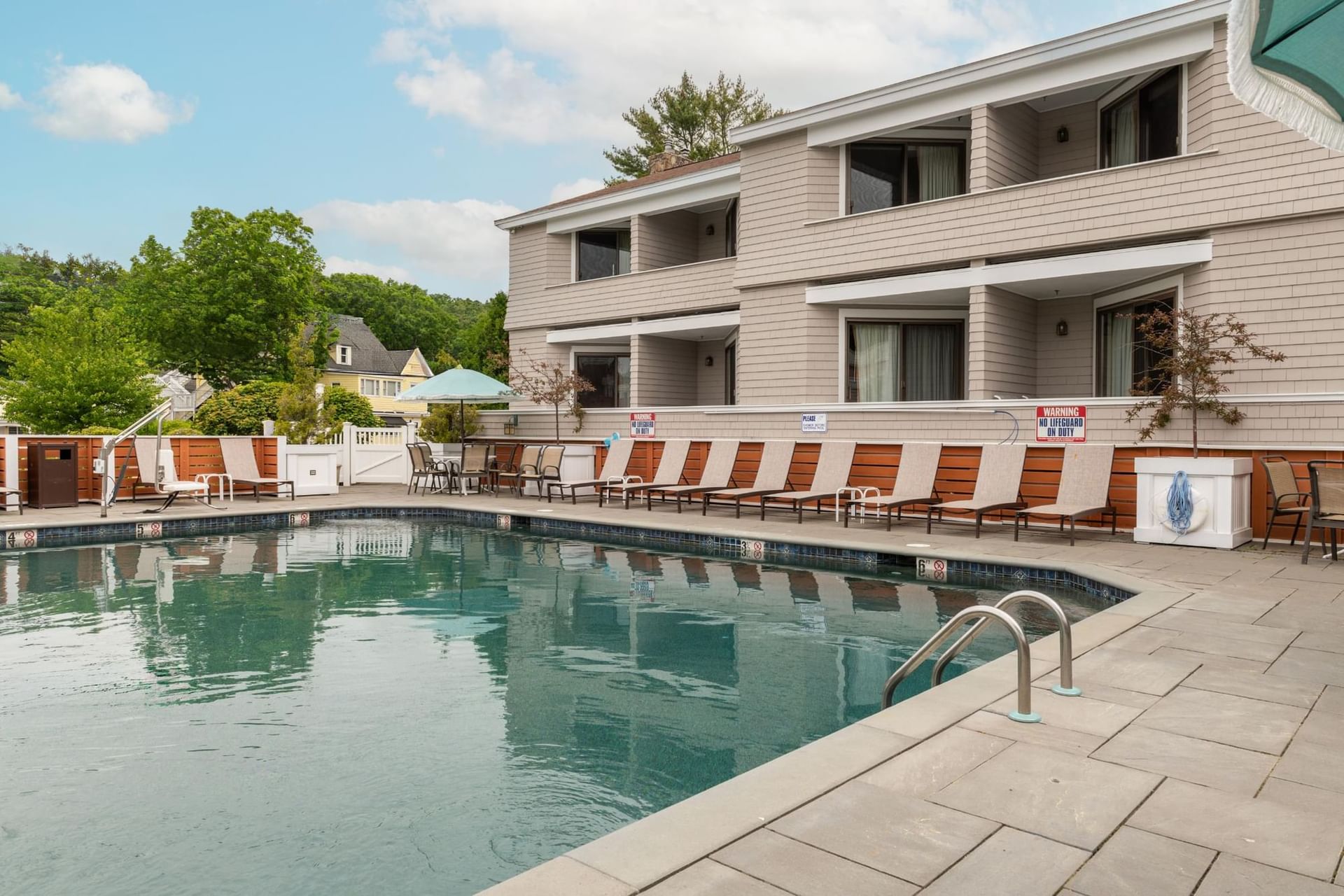 A hotel pool with lounge chairs and a building in the background.
