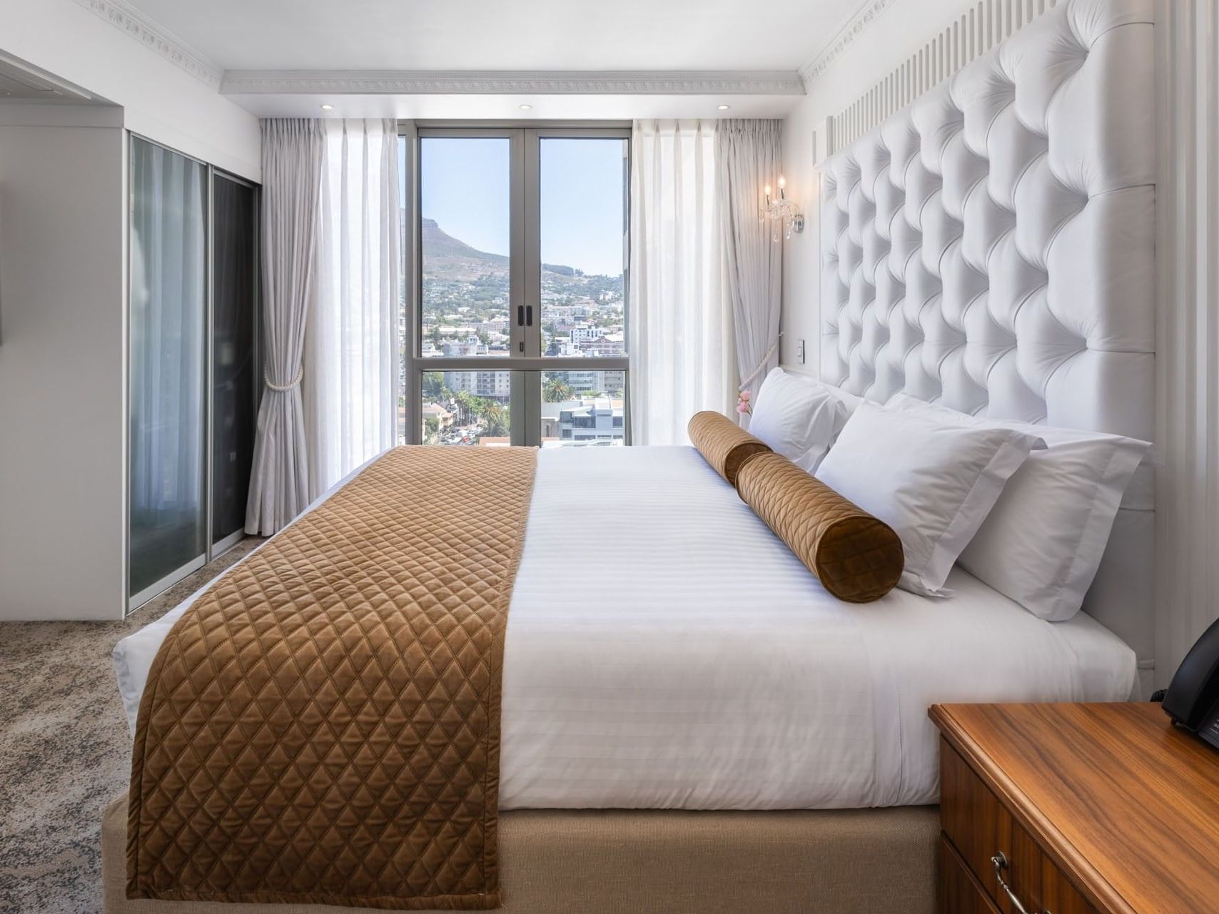 Three Bedroom Suite featuring a king bed with white tufted headboard and a large window with city views at Pepperclub Hotel