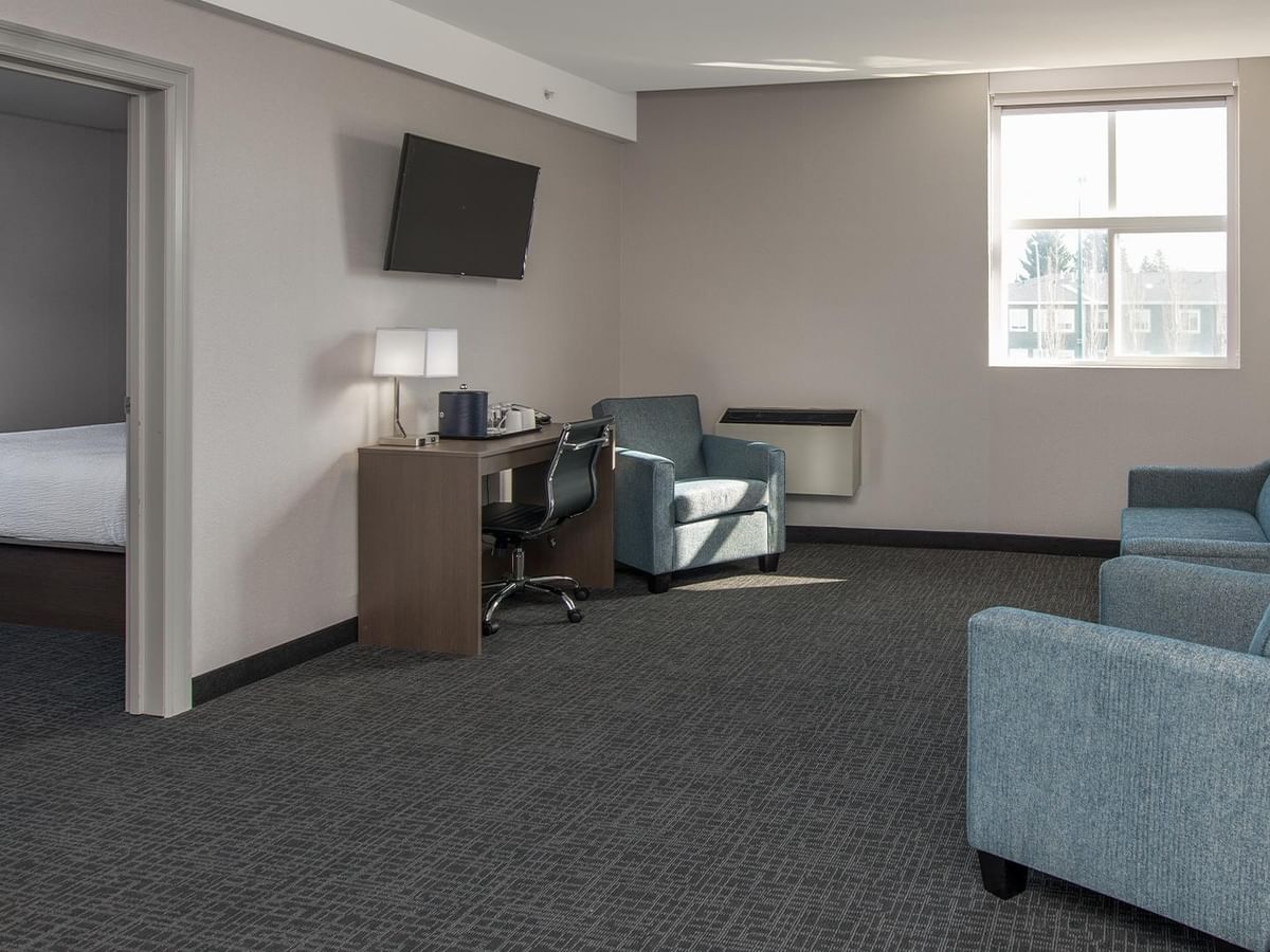 Living area of a hotel suite with couch and TV.