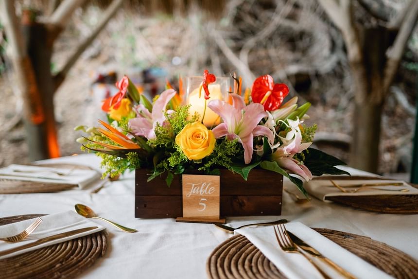 Floral centerpiece in a wooden box on a table with gold cutlery at Morgan's Rock Reserve & Ecolodge
