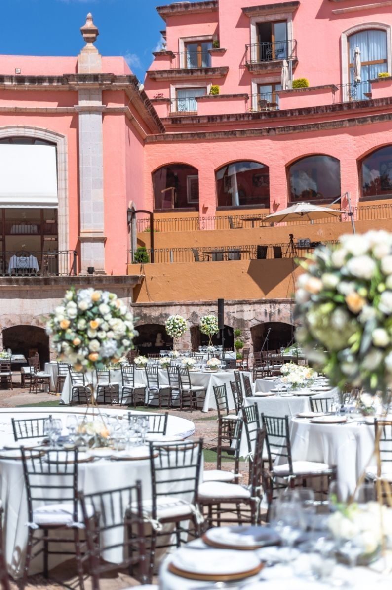 Floral towers by white tables under a pink building near the courtyard at Camino Real Pedregal Mexico