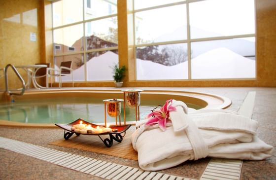 Close-up of candles & bathrobe by a jacuzzi at Honor’s Haven Retreat