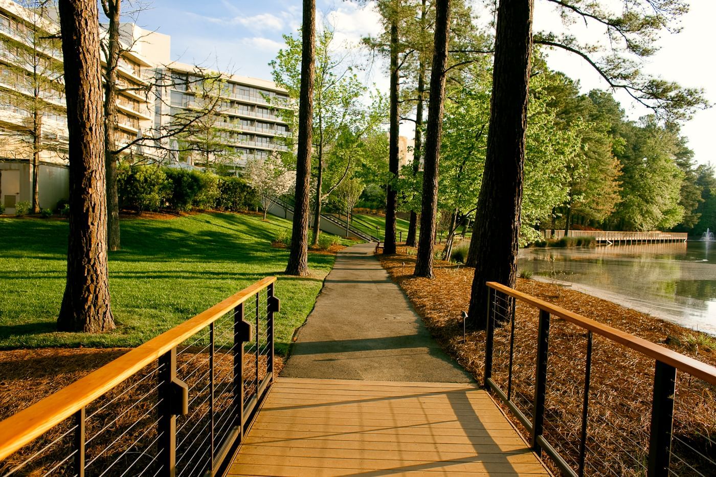 Pathway by the lake with an exterior view of the hotel at Umstead Hotel and Spa