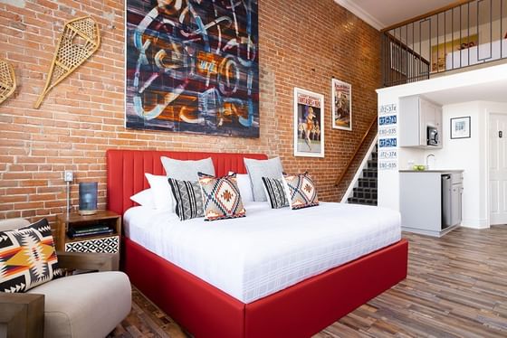 King bed, nightstand, cozy lounger & stairway in Superior Loft with wall arts at Retro Suites Hotel