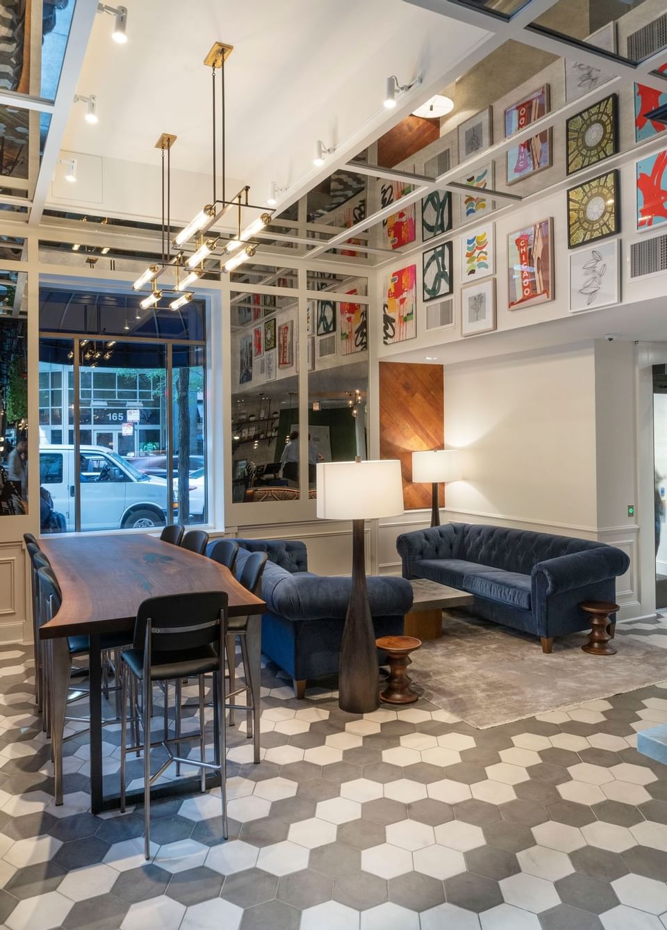 Lobby with blue sofas beside a long wood table under framed Chicago artwork and pendant lights at Hotel Saint Clair
