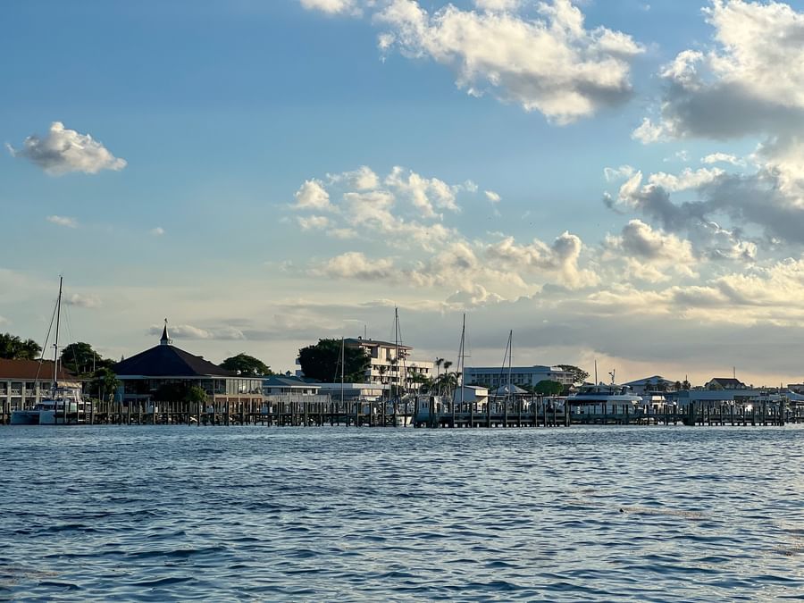Wooden pier by coastal buildings under a vast sky surrounding blue harbor water near Warwick Paradise Island Bahamas