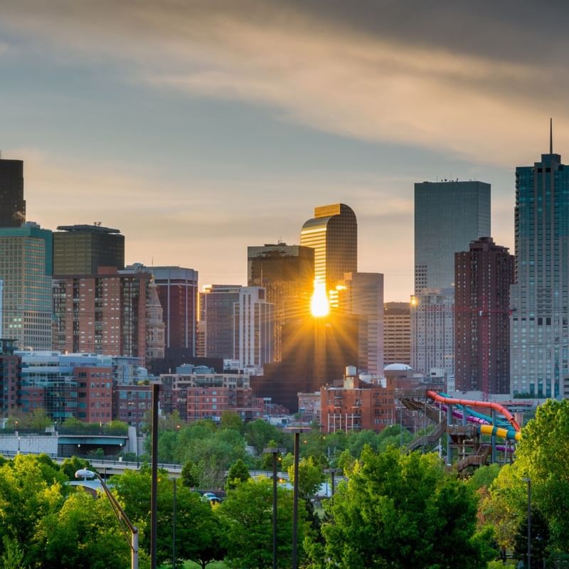 Sunrise over a vibrant downtown skyline near Warwick Hotels and Resorts in Denver, with sunlight reflecting off skyscrapers