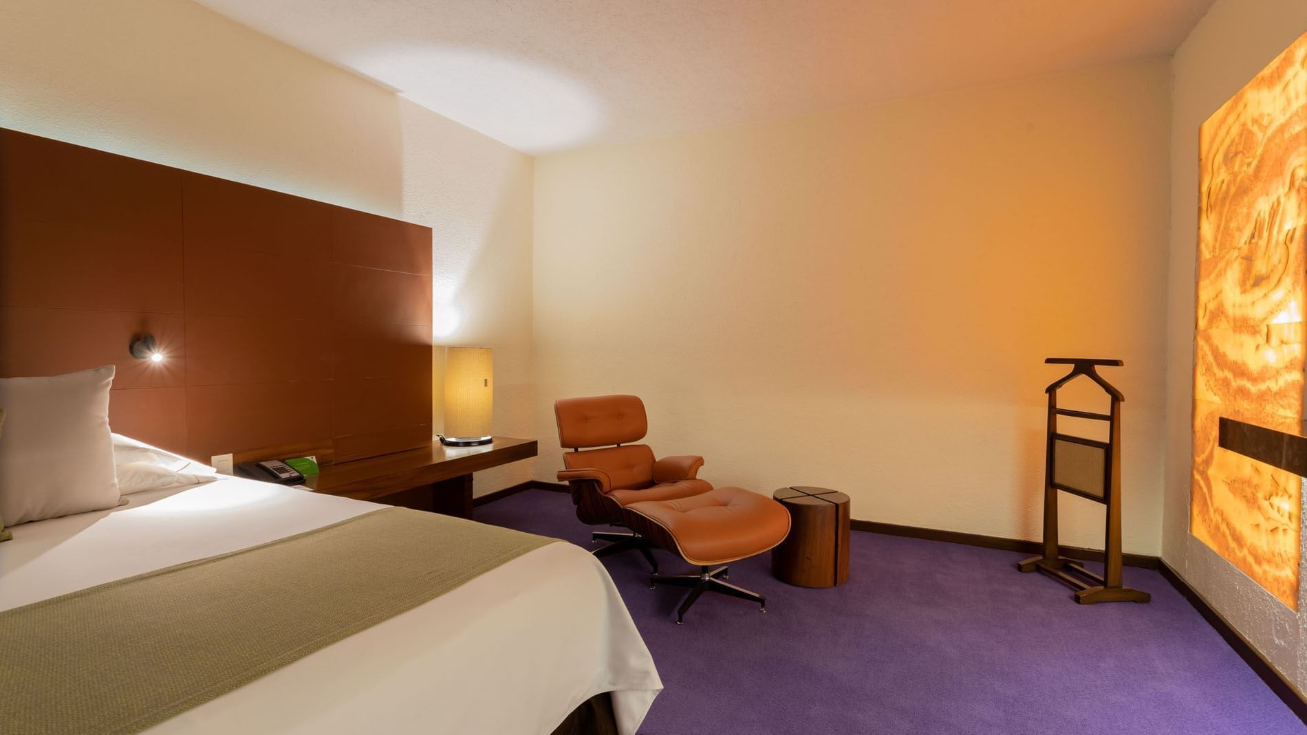Suite Junior King con sillón de cuero, otomana y alfombra púrpura en Camino Real Polanco México