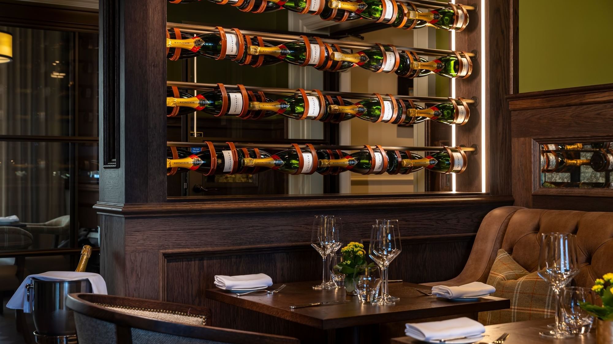 Wine bottles neatly stacked in a glowing rack above the dining table, with fine glasses in the Bar inside the Dunluce Lodge