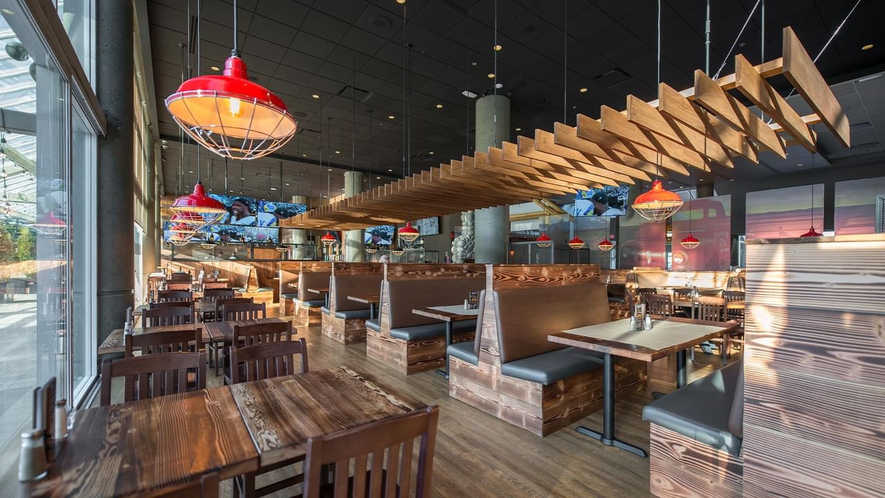 Interior of the hotel restaurant with wooden tables, booths, and red pendant lights.