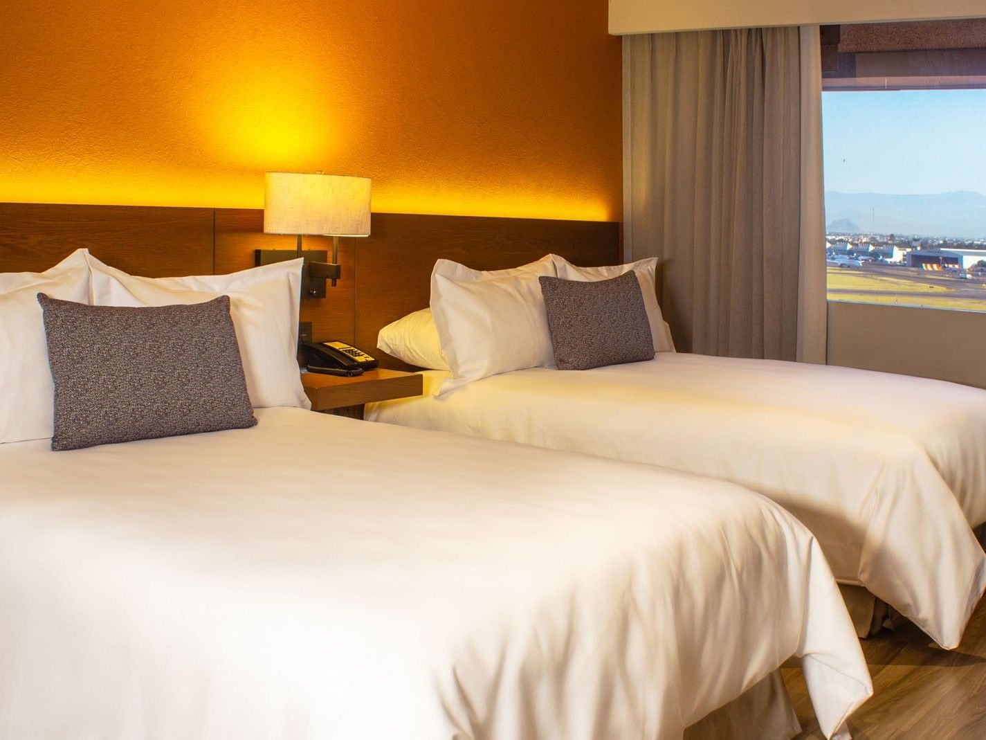 2 Double Deluxe Superior room featuring twin beds with an orange accent wall by the window at Camino Real Aeropuerto Mexico