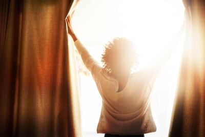 Femme ouvrant les rideaux de l'hôtel