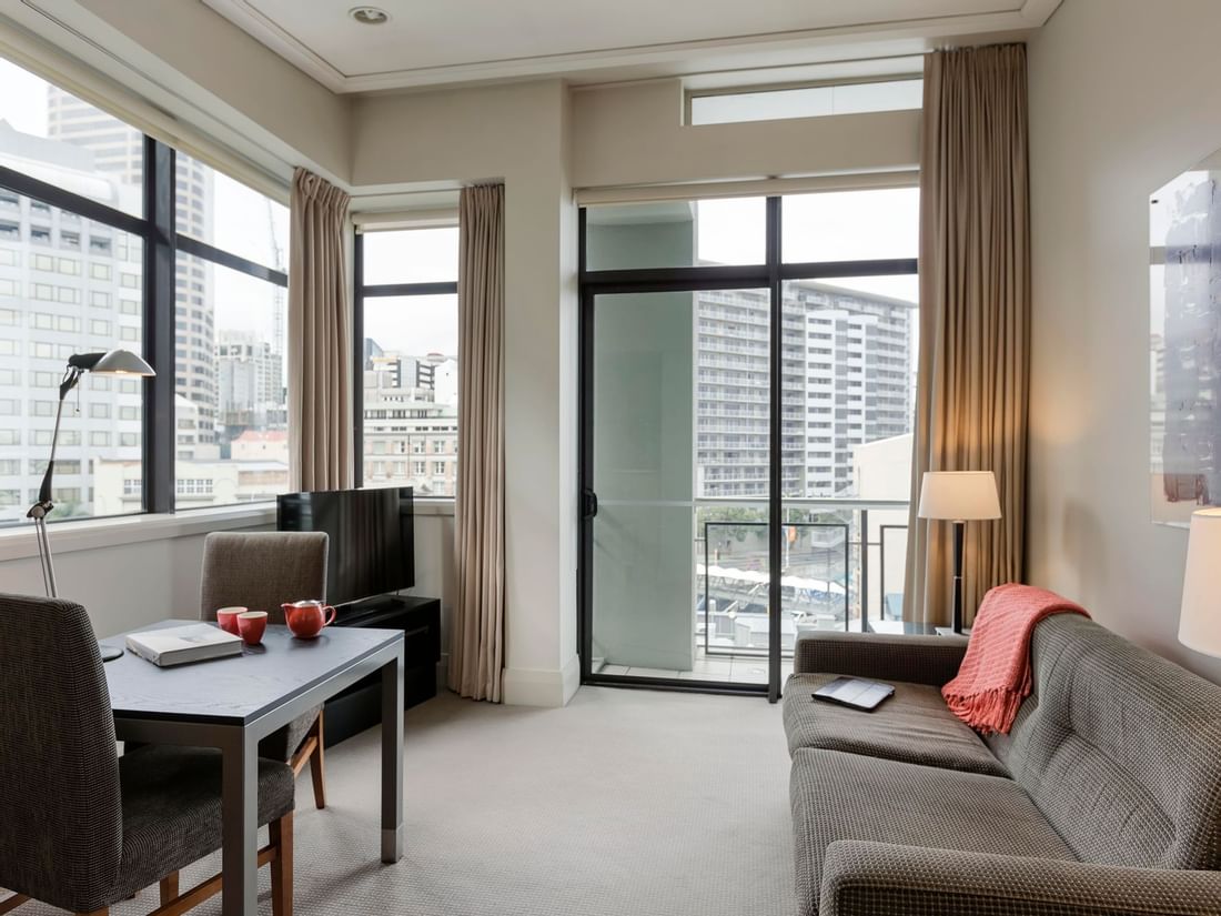 Dining table with TV lounge by the large window in City View One Bedroom Suite at the Sebel Auckland Viaduct Harbour