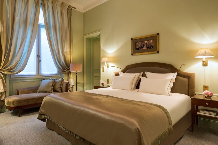 Bed with couch by the window in Deluxe Suite Parisienne at Hotel Westminster Paris