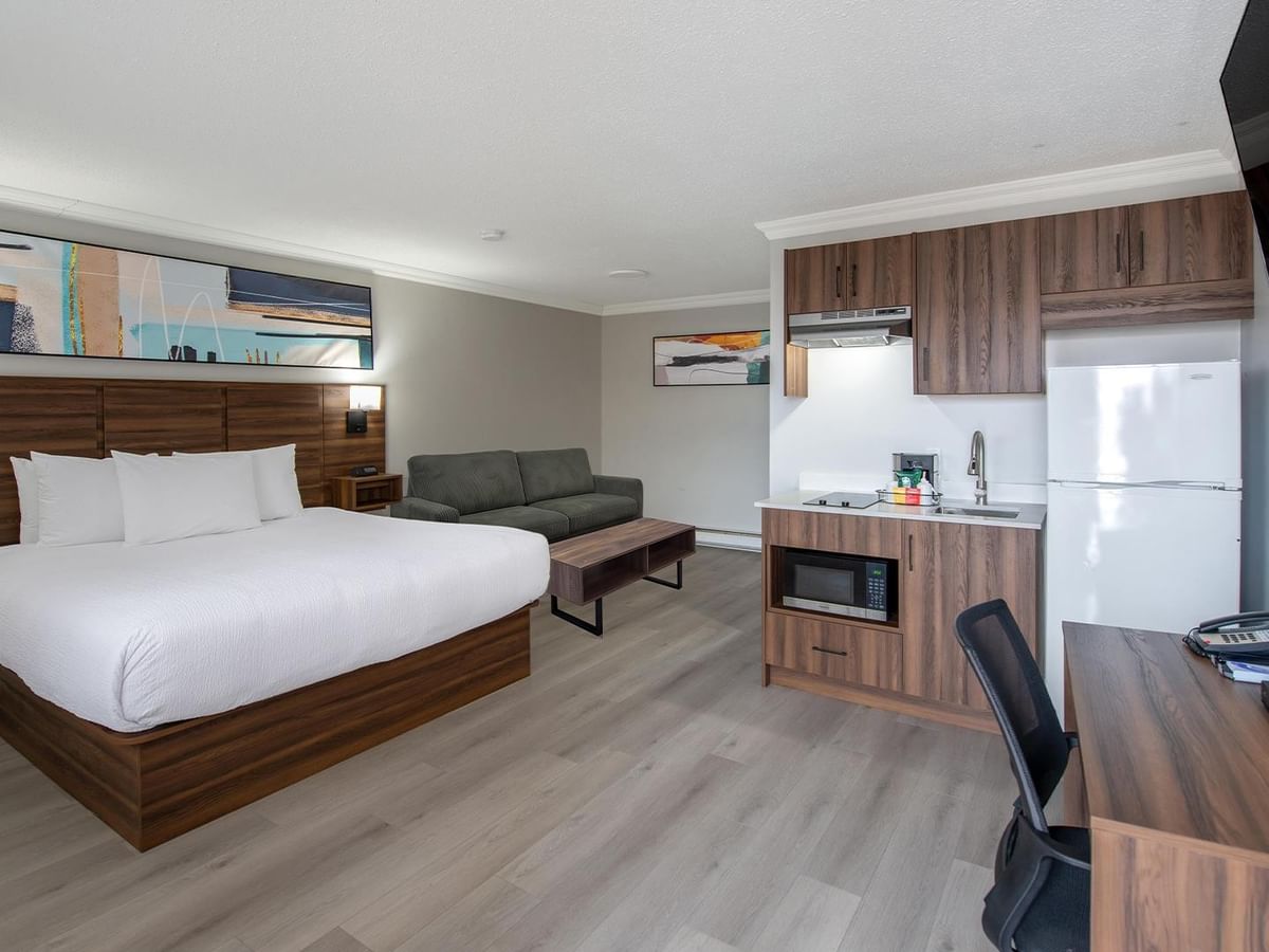 guest room with a king bed, sofa, kitchenette, work desk and flat-screen TV at Coast Dawson Creek Hotel
