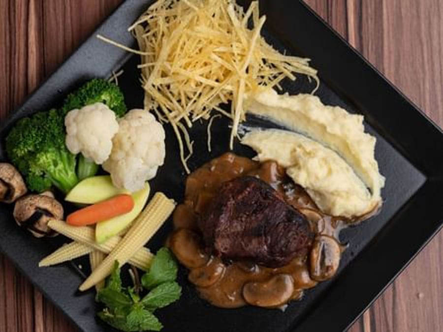 Grilled steak served by mashed potatoes and matchstick fries surrounding steamed vegetables at Warwick Al Jubail