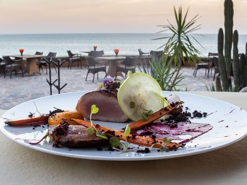 Carne sellada con zanahorias en una mesa con vista al mar en el restaurante de Hacienda Del Mar, Los Cabos.