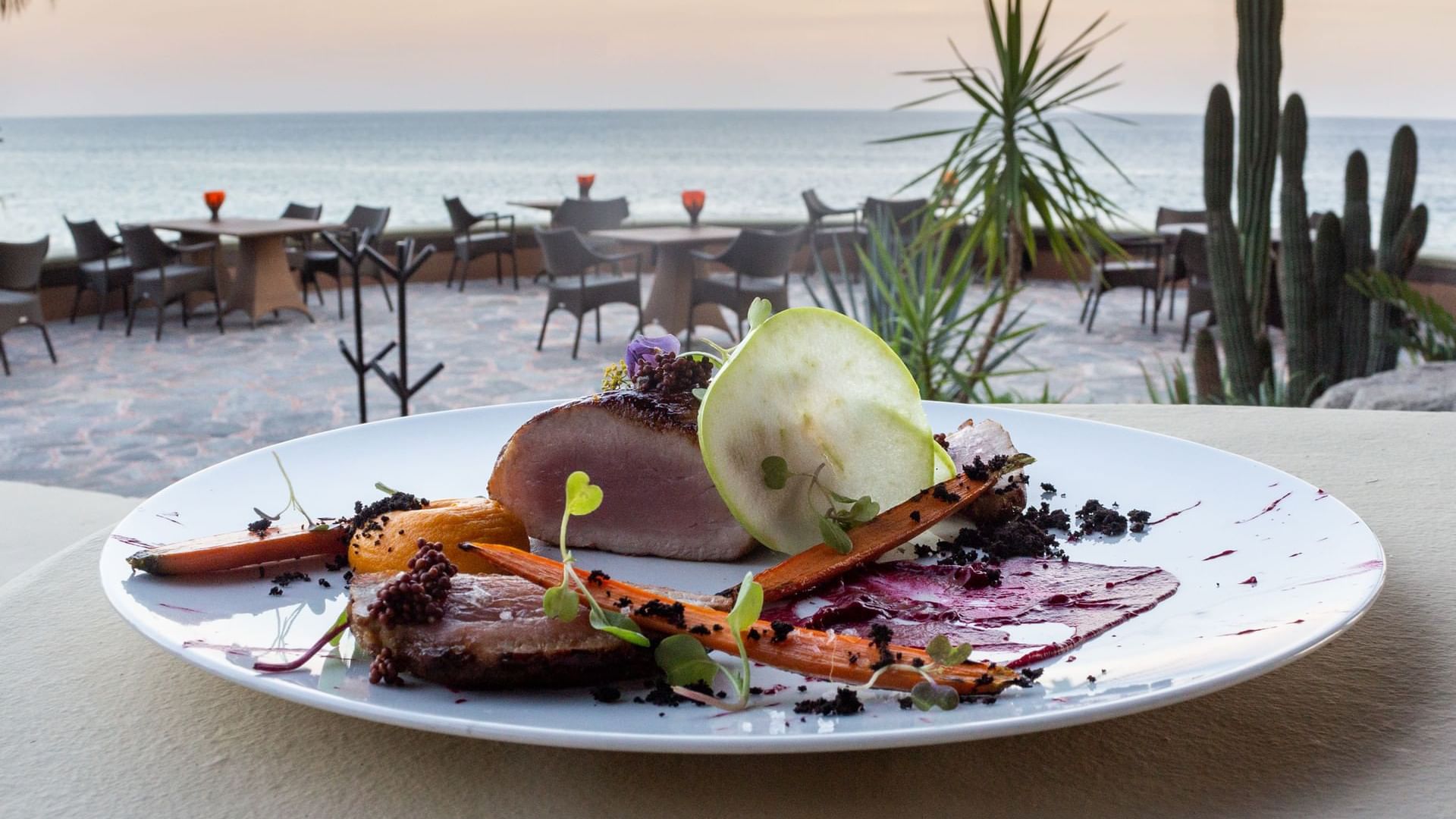Carne sellada con zanahorias en una mesa con vista al mar en el restaurante de Hacienda Del Mar, Los Cabos.