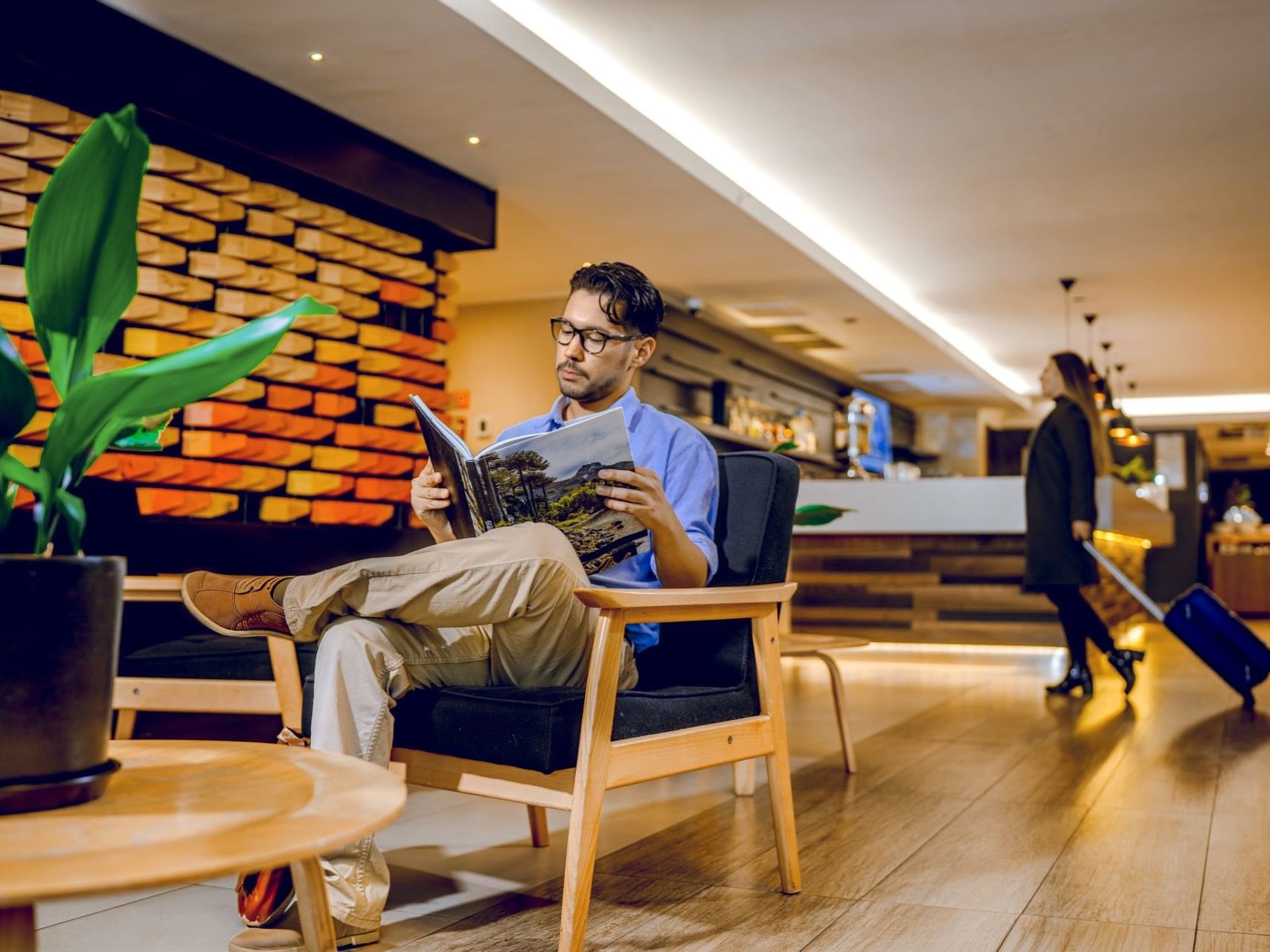 Un hombre leyendo un libro en el vestíbulo del hotel HCC Costanera Concepción.