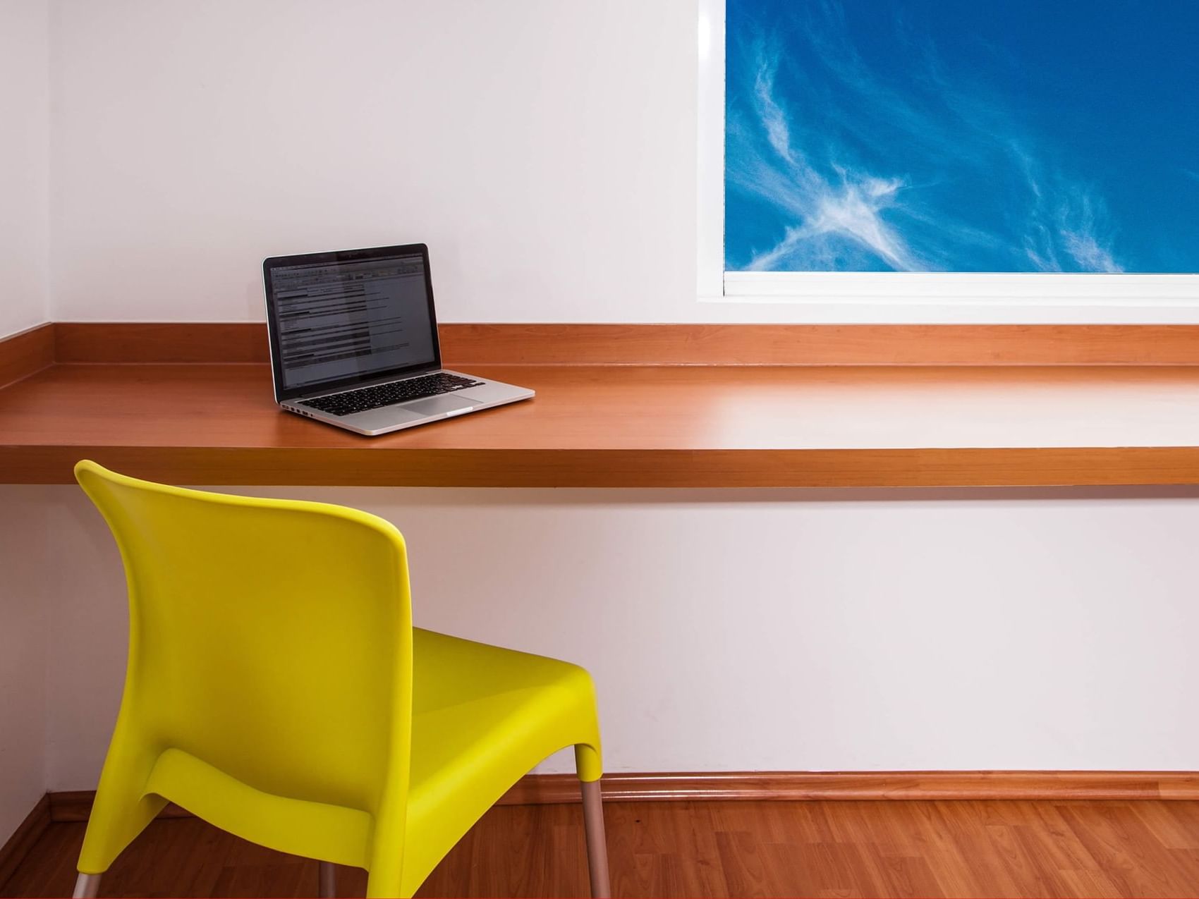 Laptop on a wall-mounted working desk with a chair, One Hotels