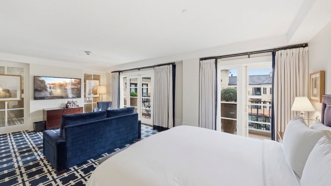 Spacious king suite with blue sofa, patterned carpet, and balcony doors at el PRADO Hotel in Palo Alto.