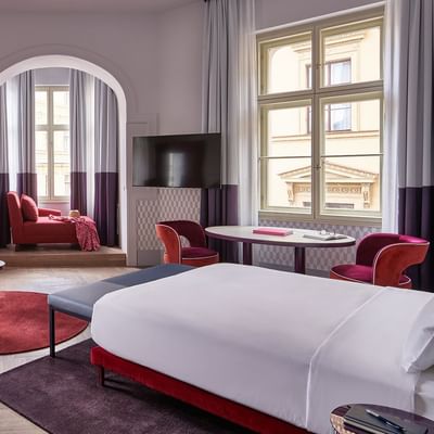 Bed, Red sofa & TV in Junior Suite at Falkensteiner Hotels