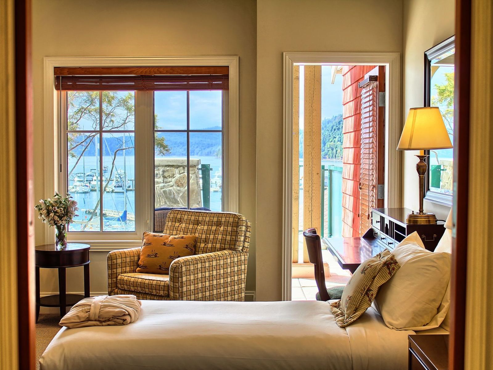 Comfy bed and sofa with balcony view in Twin Lodge Room at Poets Cove Resort & Spa