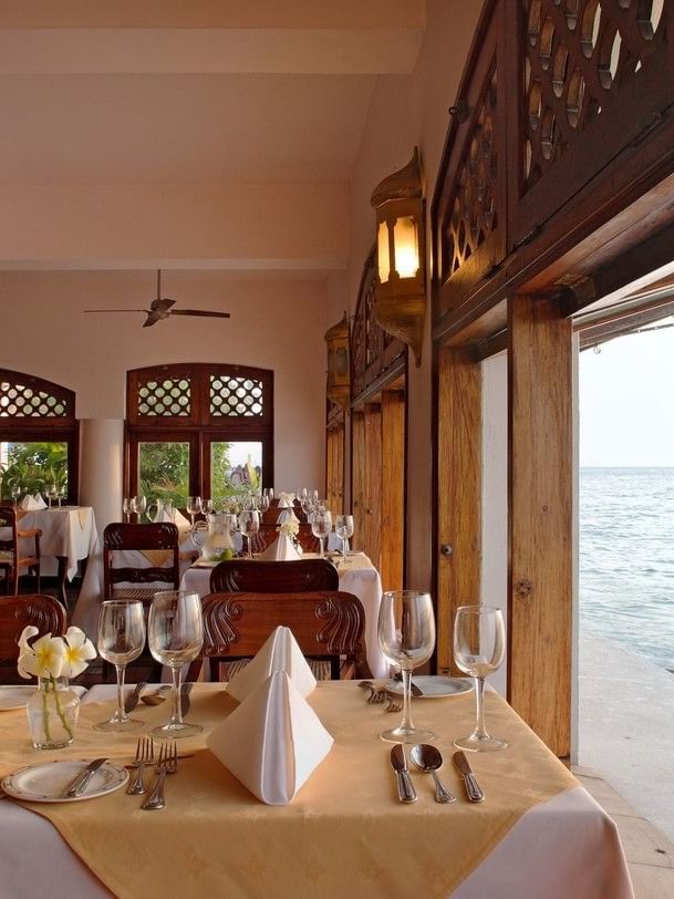 Elegant dining area with ocean view and dhow boat at Zanzibar Serena Hotel in Zanzibar