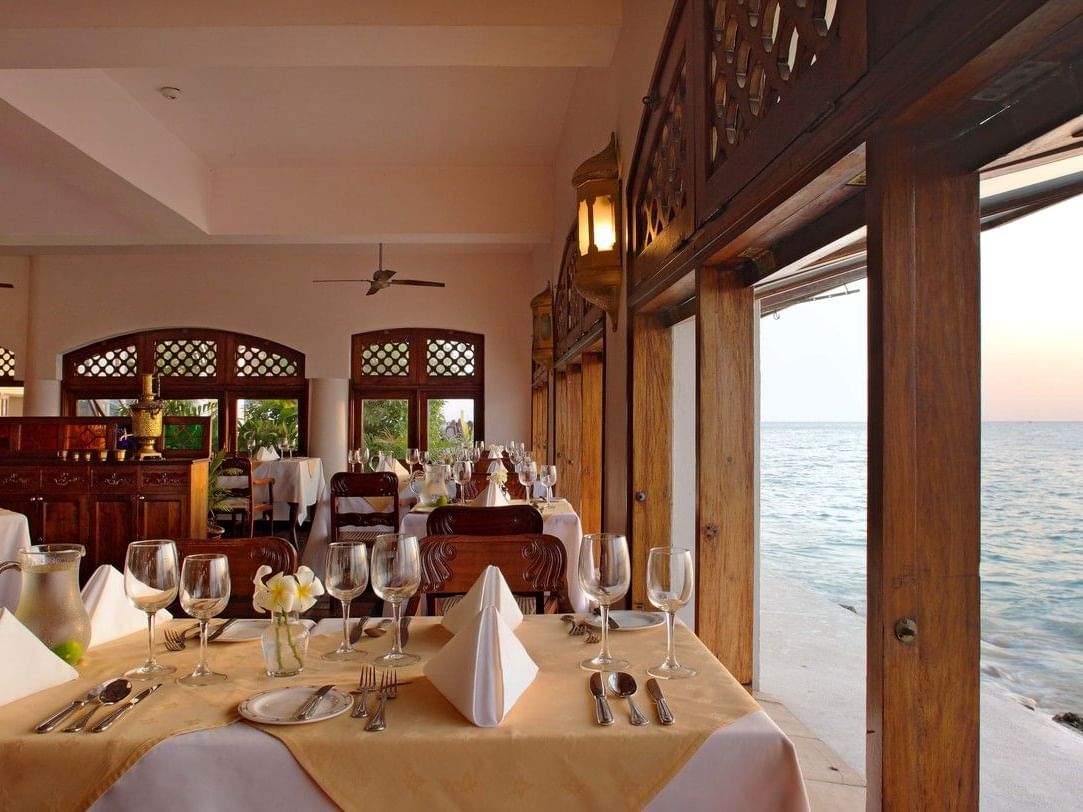 Elegant dining area with ocean view and dhow boat at Zanzibar Serena Hotel in Zanzibar.