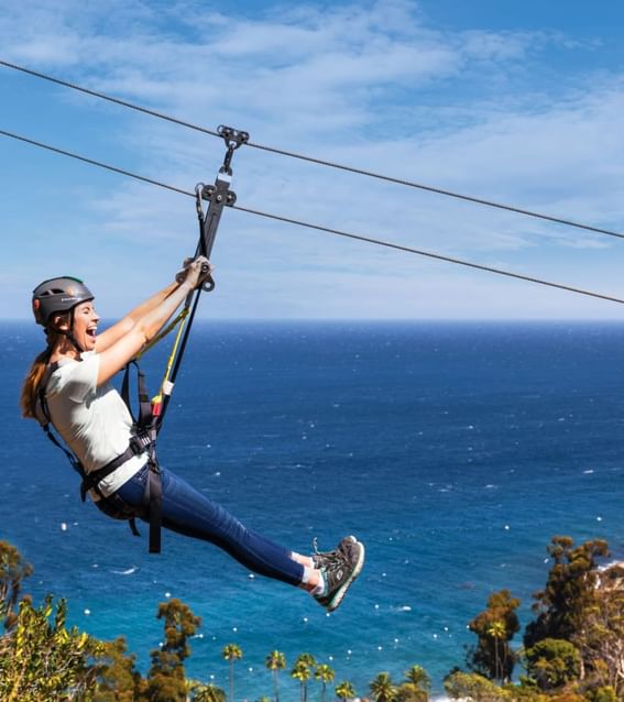 Woman gliding on Catalina Island zipline with ocean backdrop near Catalina Island Company