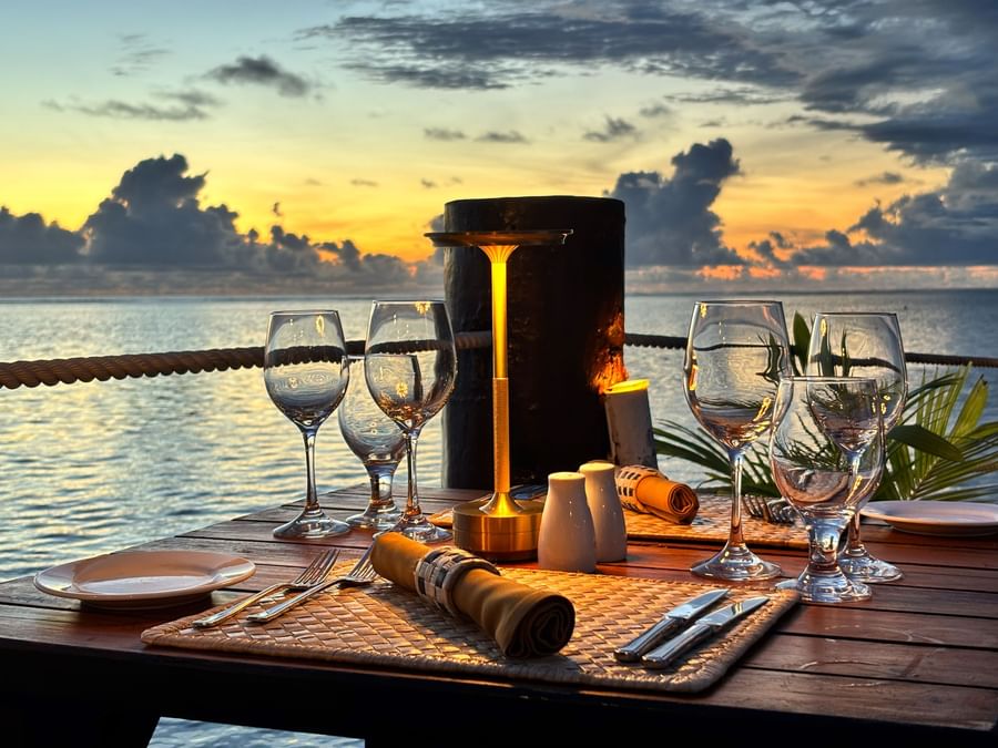 Outdoor dining setup with ocean view at sunset at Warwick Fiji Resort and Spa.